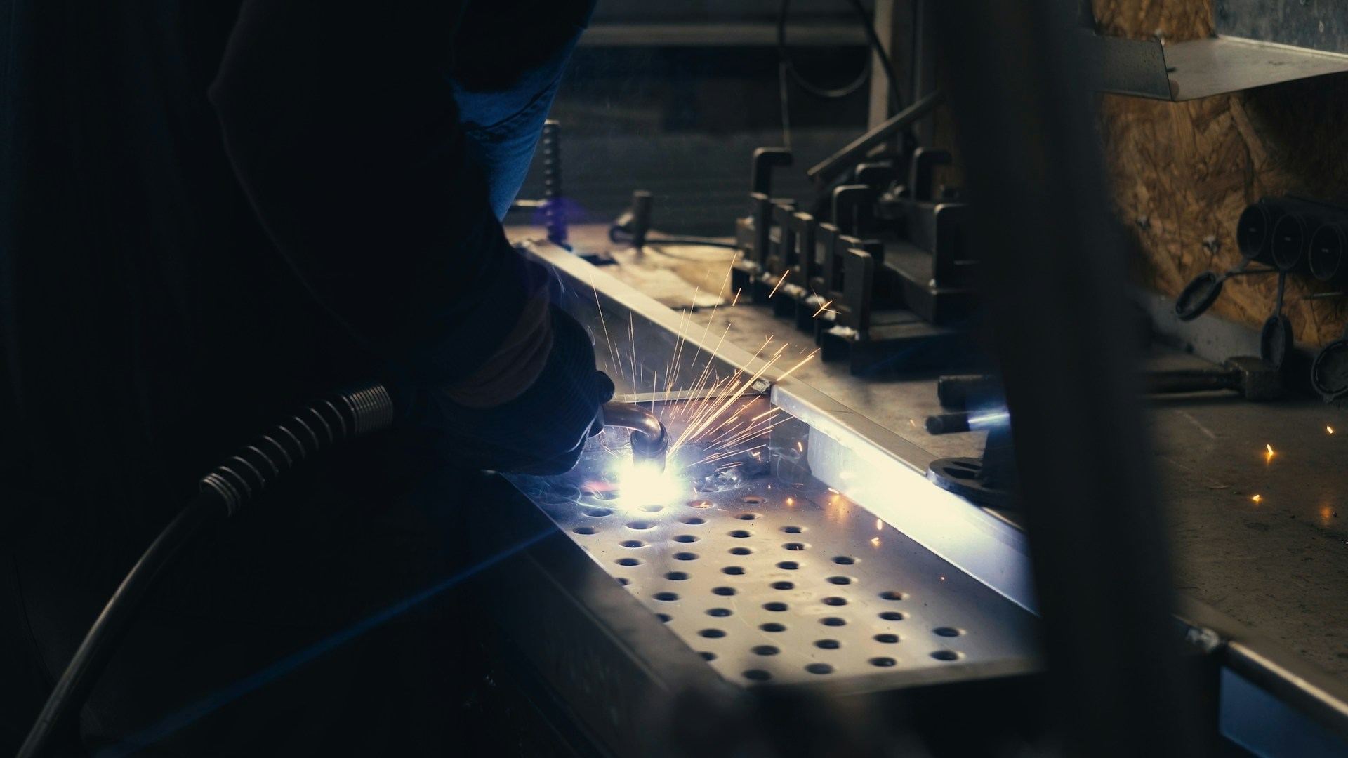 Welder at work, sparks off a steel bench